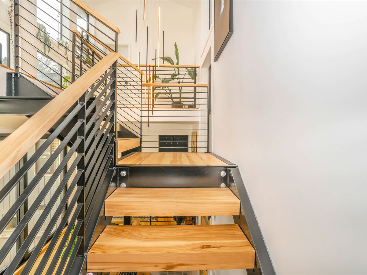 Treppe mit schwarzem Metallgeländer und Handlauf aus Holz